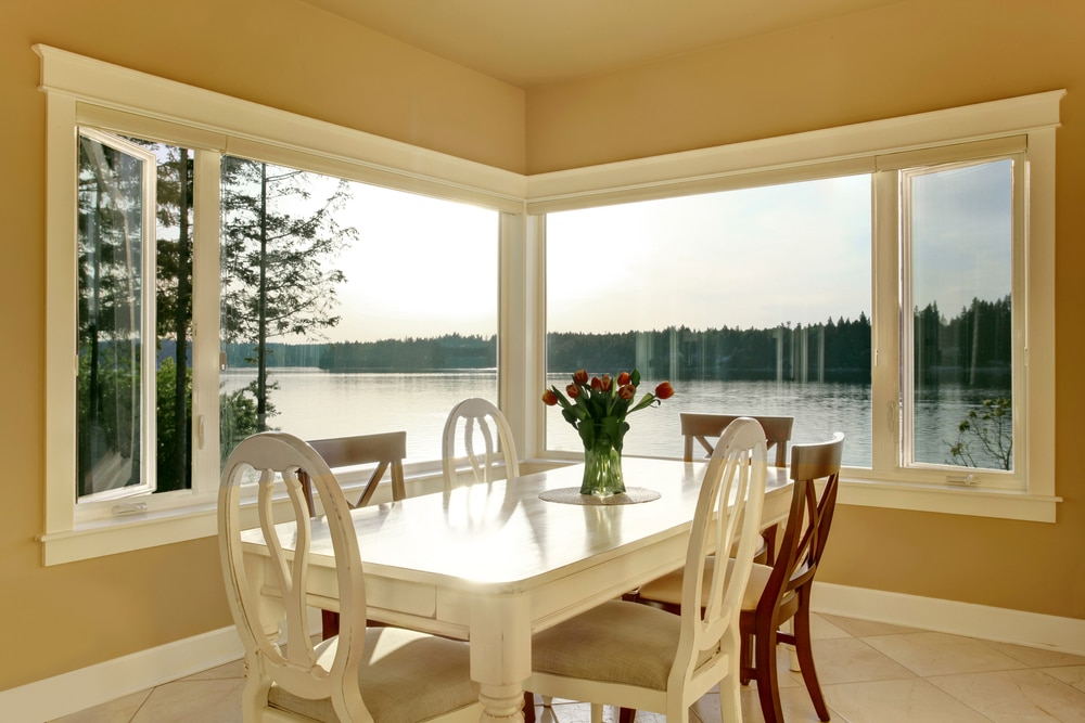 dining room interior with casement windows overlooking a water view